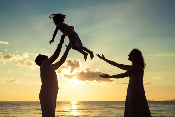 Silueta de familia feliz que juega en la playa al atardecer —  Fotos de Stock