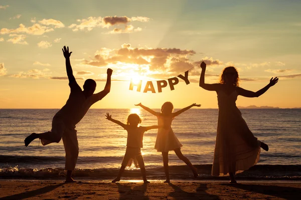 Gelukkig familie staande op het strand op de zonsondergang keer. — Stockfoto