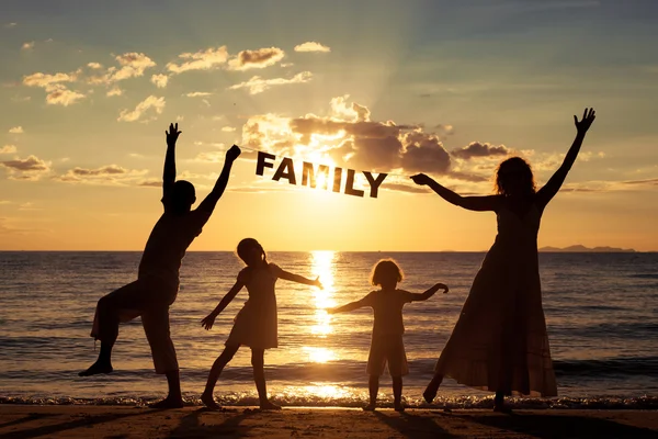 Ευτυχισμένη οικογένεια στέκεται στην παραλία στο τον χρόνο ηλιοβασίλεμα. — Φωτογραφία Αρχείου