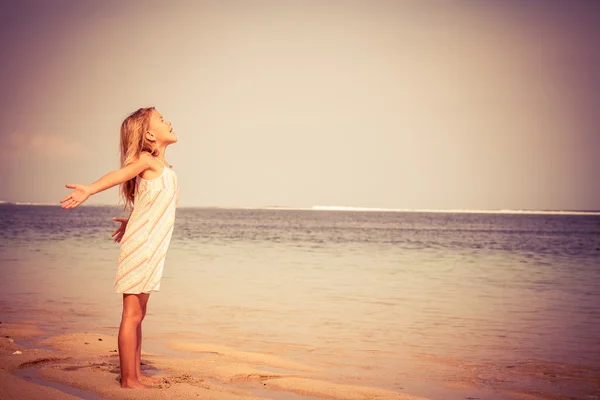 Lycklig liten flicka stående på stranden — Stockfoto