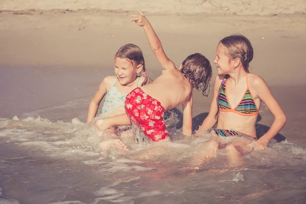 Drei glückliche Kinder spielen am Strand — Stockfoto