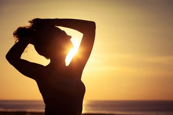 Frau mit offenen Armen unter dem Sonnenuntergang auf See — Stockfoto