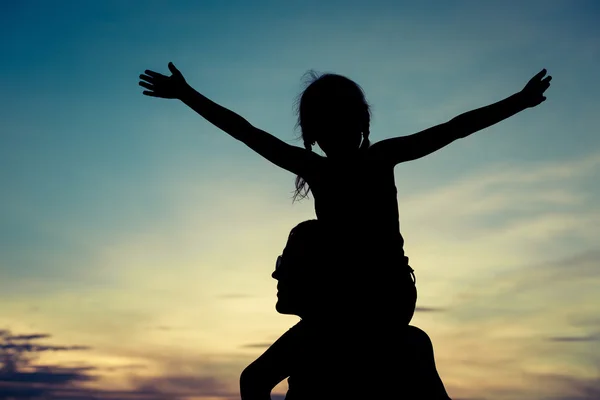 Far och dotter spelar på stranden vid solnedgången tid. — Stockfoto