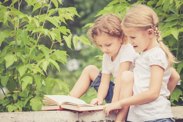 Kleine Jungen und Mädchen mit Buch sitzen im Park — Stockfoto