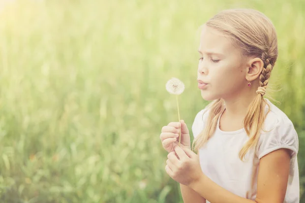 Söt liten flicka spelar med blommor i park — Stockfoto