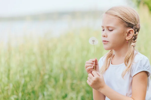 Χαριτωμένο μικρό κορίτσι παίζει με τα λουλούδια στο πάρκο — Φωτογραφία Αρχείου