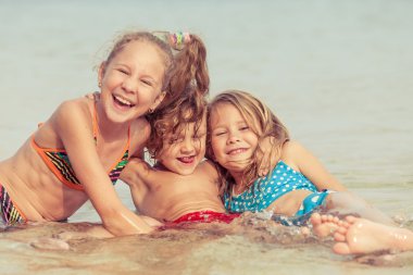 Üç mutlu çocuklar kumsalda oynarken