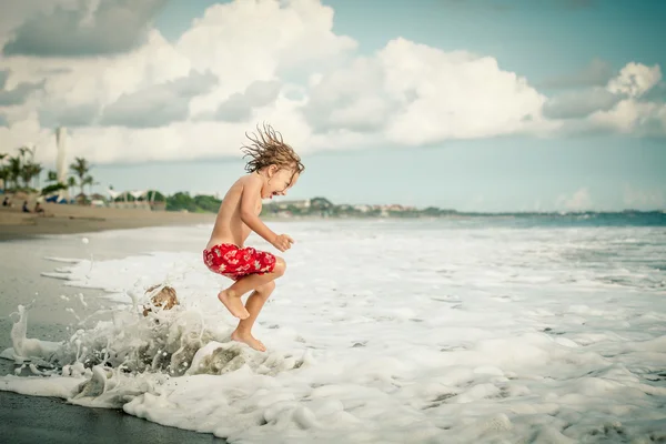 Porträt eines kleinen Jungen, der am Strand springt — Stockfoto