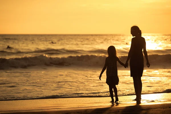 Mor och dotter spelar på stranden vid solnedgången tid. — Stockfoto