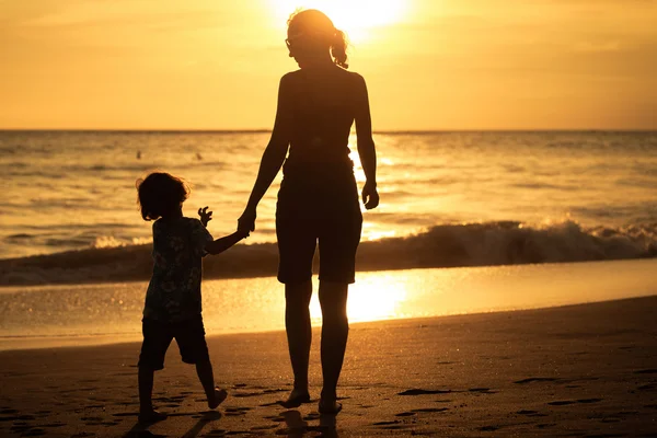 Mère et fils jouant sur la plage au coucher du soleil . — Photo