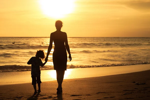 Moeder en zoon spelen op het strand op de zonsondergang keer. — Stockfoto