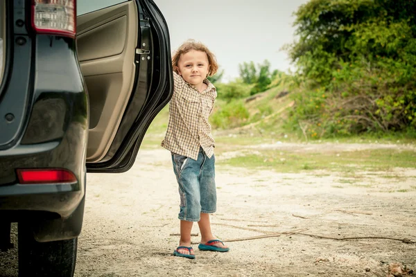 Liten pojke står nära bilen — Stockfoto