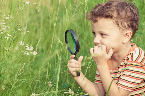 Menino feliz explorando a natureza com lupa — Fotografia de Stock