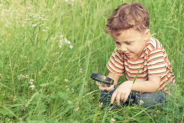 Menino feliz explorando a natureza com lupa — Fotografia de Stock