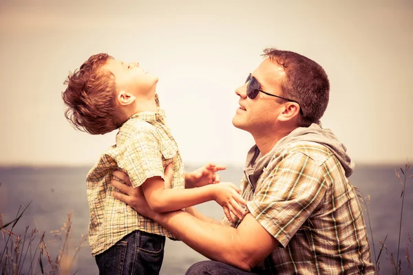 Padre e hijo jugando en el parque cerca del lago durante el día . — Foto de Stock