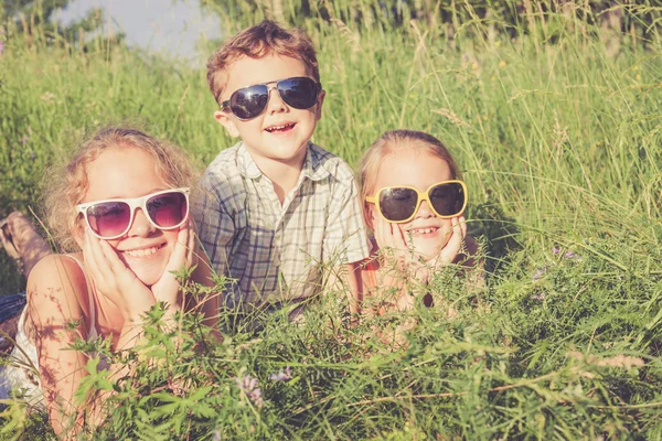 Três crianças felizes brincando perto da árvore — Fotografia de Stock