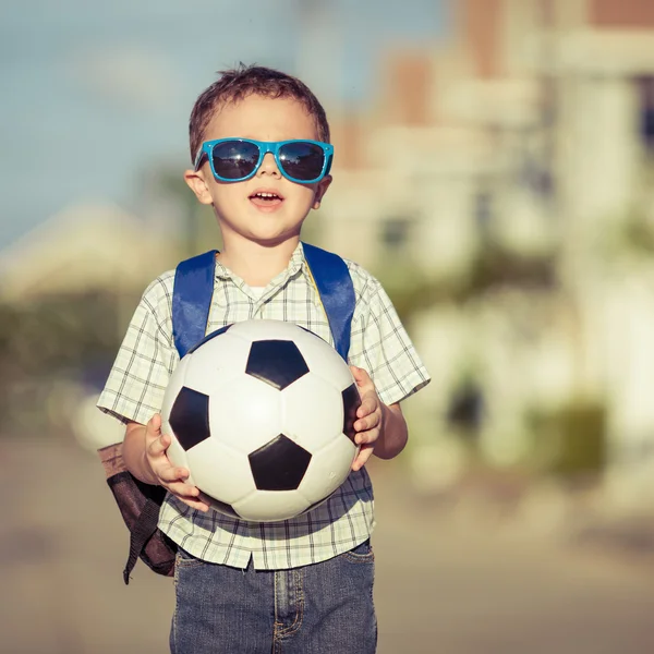 Kaukasischer kleiner Junge steht auf der Straße und hält seinen Fußball — Stockfoto