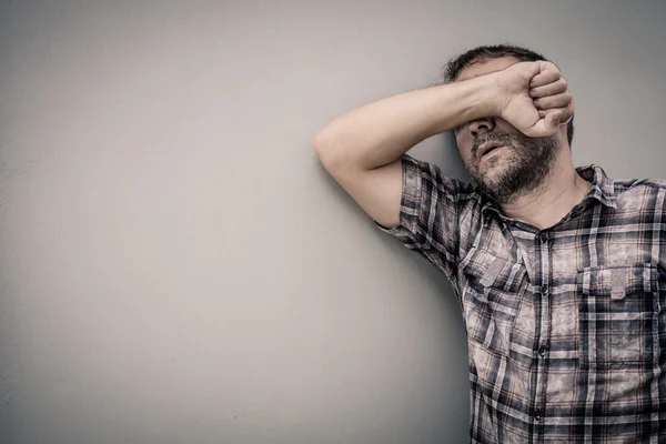 Porträtt en ledsen man står nära en vägg och täcker sitt ansikte — Stockfoto