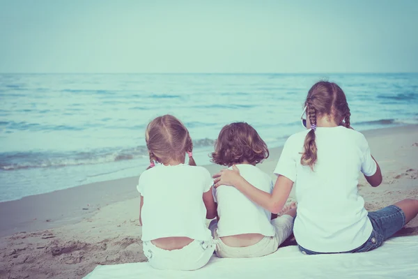 Dvě sestry a bratr sedí na pláži — Stock fotografie