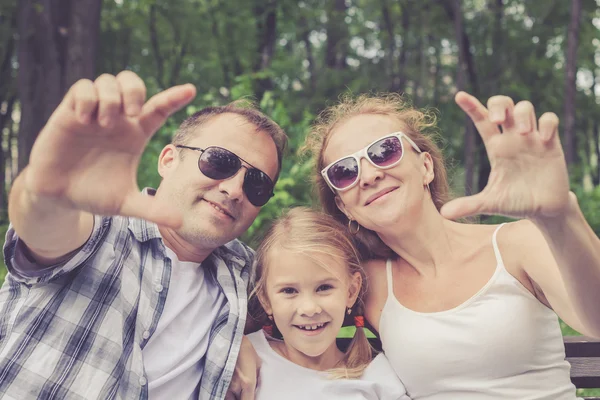 Família feliz sentado no banco no parque — Fotografia de Stock