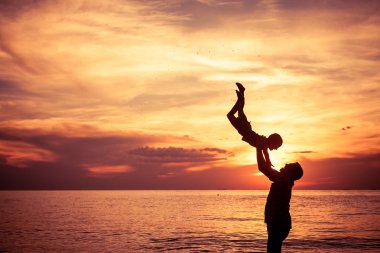 Baba ve oğul sahilde günbatımı anda oynamak.