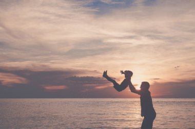 Baba ve oğul sahilde günbatımı anda oynamak.