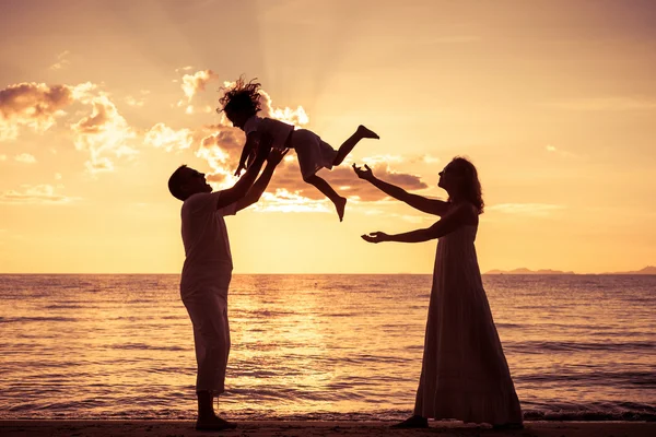 Силует щасливої сім'ї, яка грає на пляжі на сонці — стокове фото