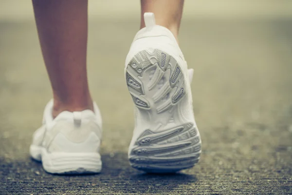 Jóvenes zapatillas de deporte en las piernas de chica en el camino —  Fotos de Stock