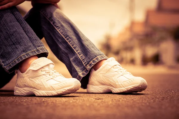 Baskets de jeunesse sur les jambes de la fille sur la route — Photo