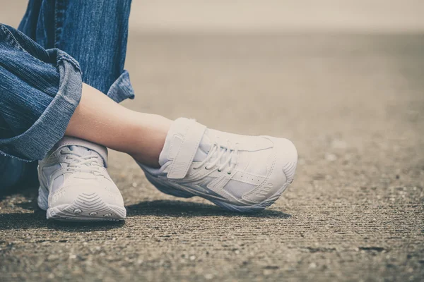 Baskets de jeunesse sur les jambes de la fille sur la route — Photo