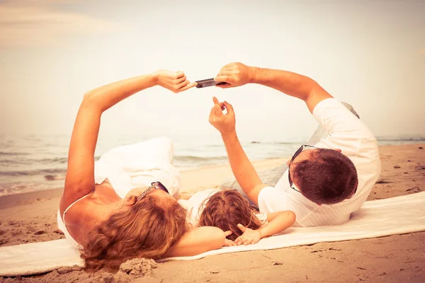 Liggend op het strand op het moment van de dag en gelukkige familie. — Stockfoto