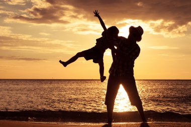 Baba ve oğul sahilde günbatımı anda oynamak.