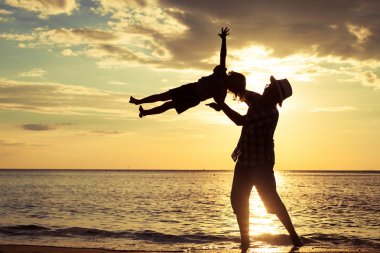 Baba ve oğul sahilde günbatımı anda oynamak.