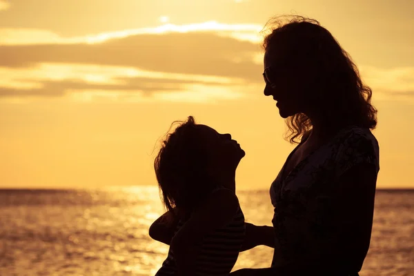 Mor og søn leger på stranden ved solnedgang tid . - Stock-foto