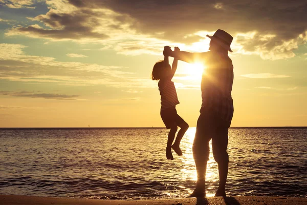 Vader en zoon spelen op het strand op de zonsondergang keer. — Stockfoto