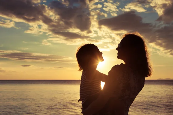 Matka i syn, gry na plaży podczas zachodu słońca. — Zdjęcie stockowe