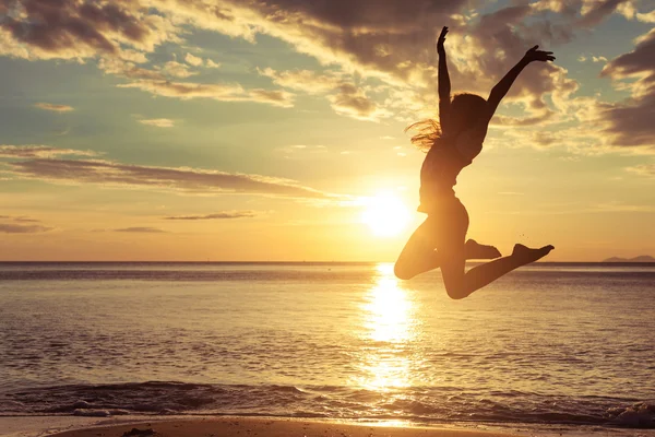 Glad flicka hoppar på stranden — Stockfoto