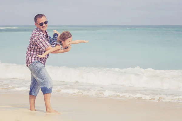 Far och son som spelar på stranden på dagarna. — Stockfoto