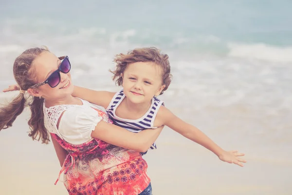 Kız ve erkek kardeş kumsalda gün anda oynamak. — Stok fotoğraf