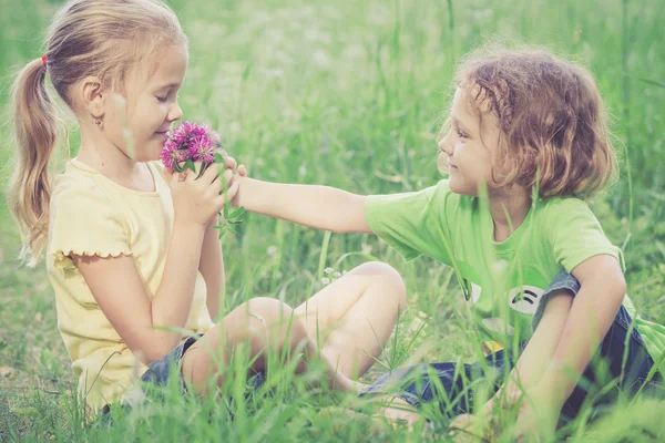 Duas crianças felizes brincando perto da árvore no dia . — Fotografia de Stock