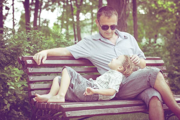 Vader en zoon spelen in het park op Bank op het moment van de dag. — Stockfoto