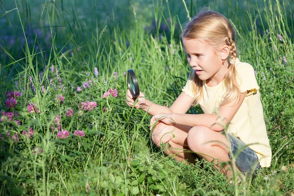 Niña feliz explorando la naturaleza con lupa — Foto de Stock