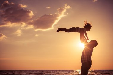 Baba ve oğul sahilde günbatımı anda oynamak.