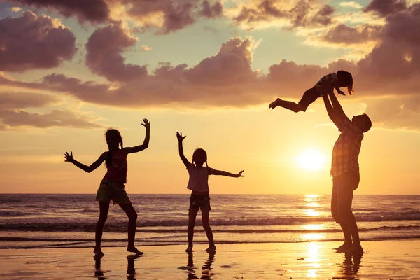 Ο πατέρας και τα παιδιά που παίζουν στην παραλία το ηλιοβασίλεμα στιγμή. — Φωτογραφία Αρχείου