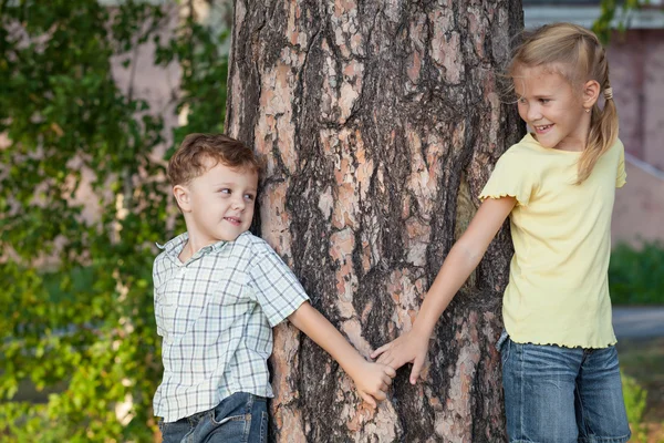 Dos niños felices jugando cerca del árbol durante el día . —  Fotos de Stock