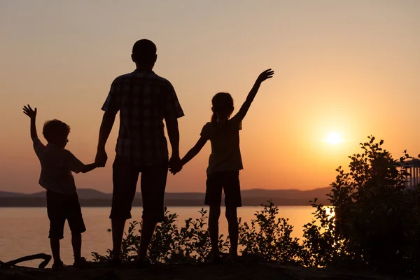 Pai e filhos brincando na costa do lago — Fotografia de Stock