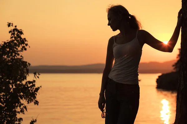 Silhouette einer Frau, die am Ufer des Sees steht — Stockfoto