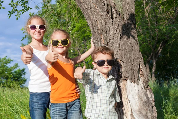 Trzy szczęśliwe dzieci bawiące się w parku w czasie dnia. — Zdjęcie stockowe