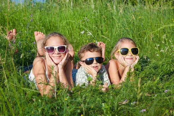 Drie gelukkige kinderen spelen in het park op het moment van de dag. — Stockfoto