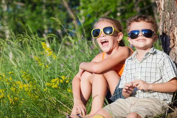 Zwei glückliche Kinder, die tagsüber in der Nähe des Baumes spielen. — Stockfoto